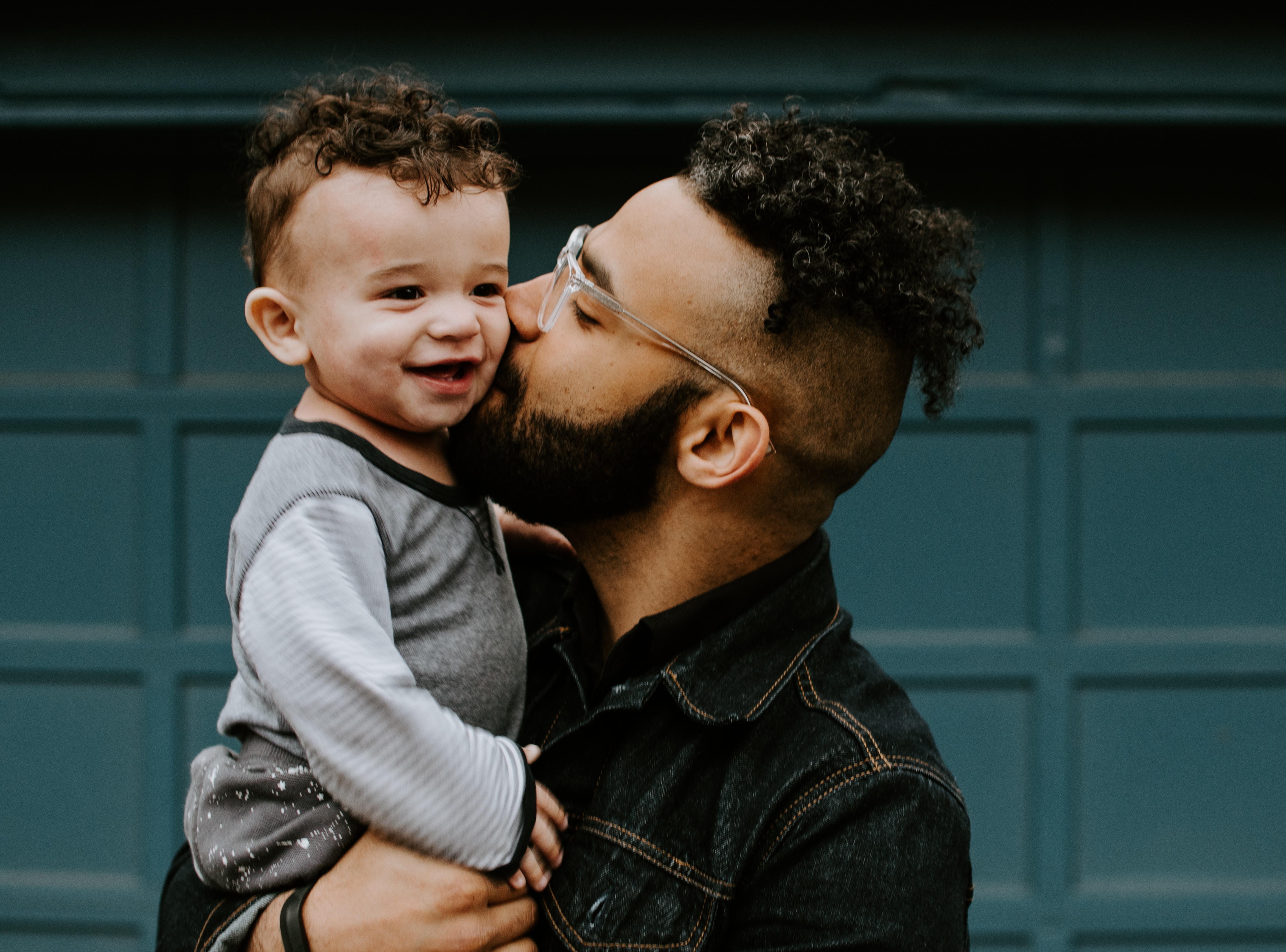 Black father holding young son and kissing his face